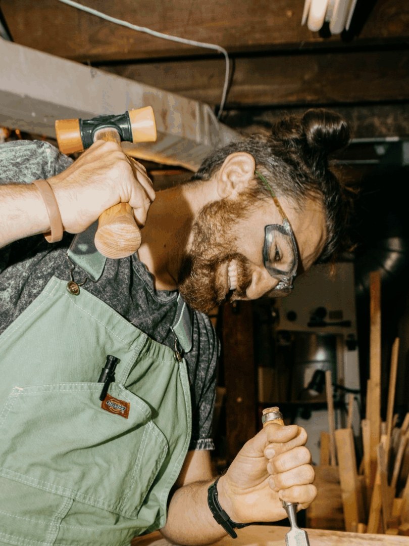 Archie Japaridze driving a chisel with a mallet at the bench