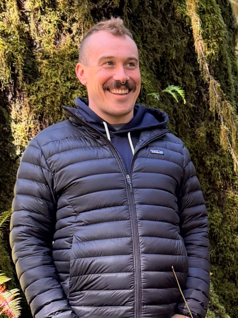 Ben Coney smiling in front of a moss-covered tree