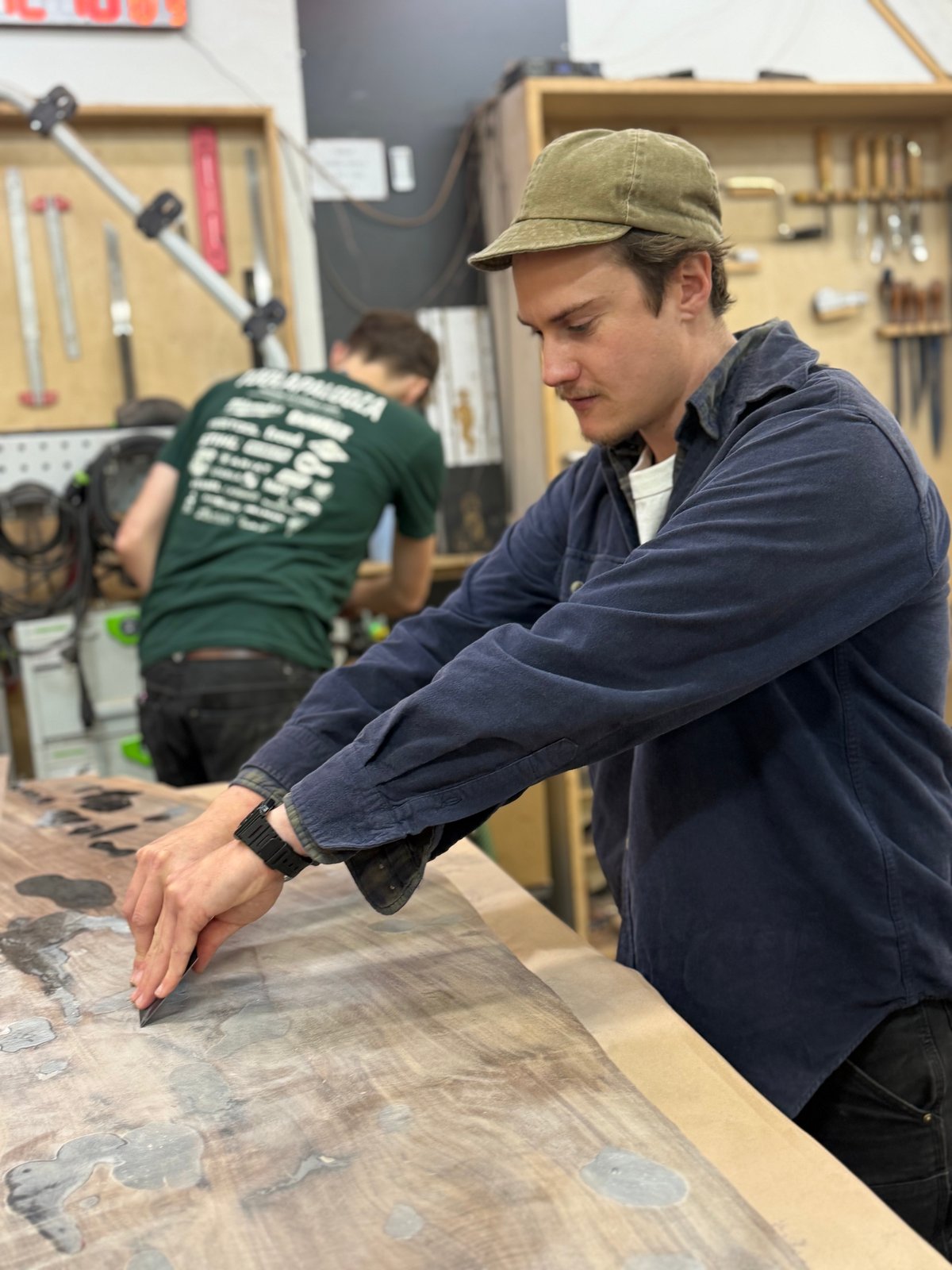 Coda Concannon working a scraper across a walnut slab top